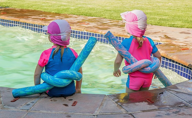 2 kids sitting at the swimming pool