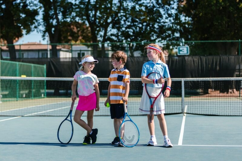 3 kids with tennis rackets at the net