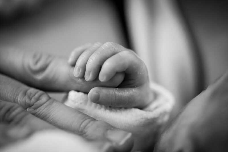 Newborn baby holding parents finger