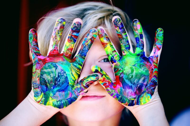 Boy with both hands cover in paint over his face