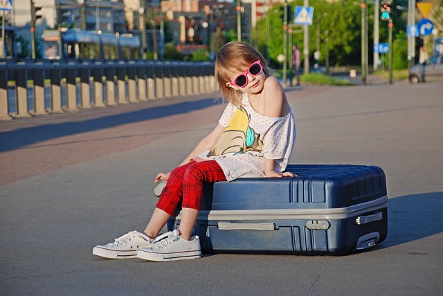 Girl sitting on large suitcase with sunglasses on