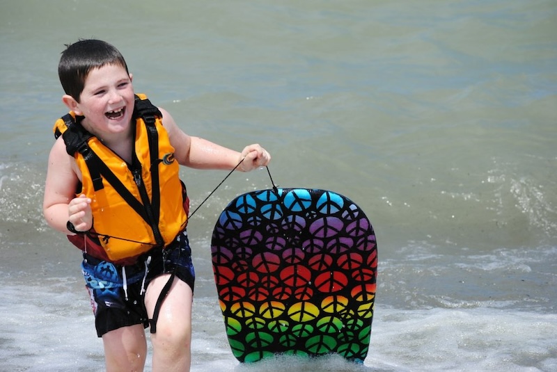 Boy at sea with life jacket and paddling board