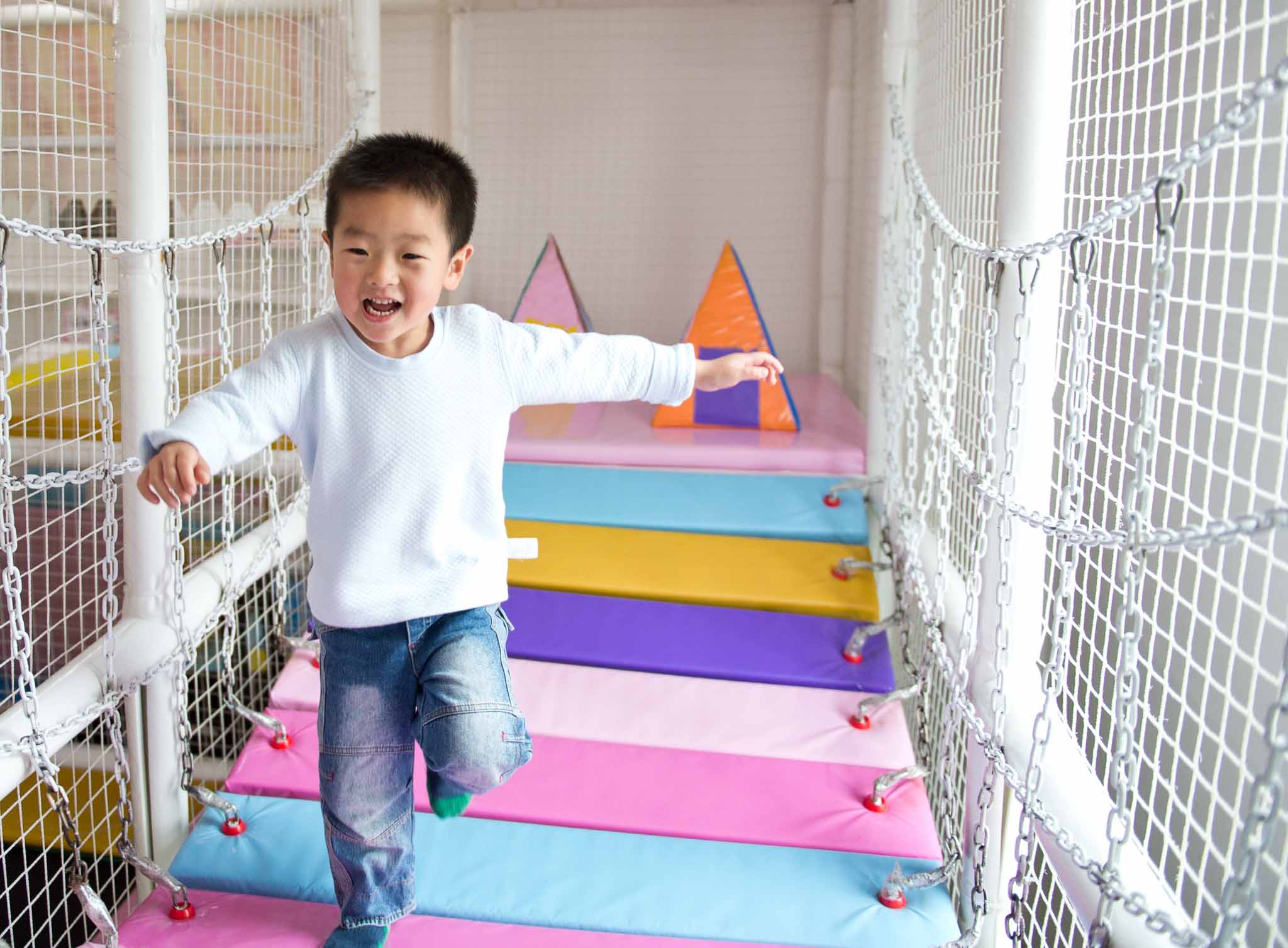 Boy crossing the bridge on a playground.