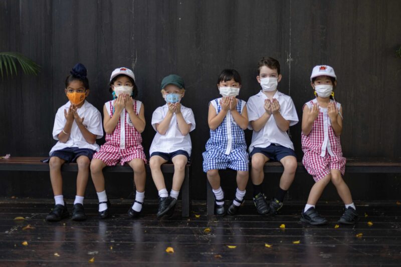 Group of Bangkok Patana young students in uniform sitting on a bench