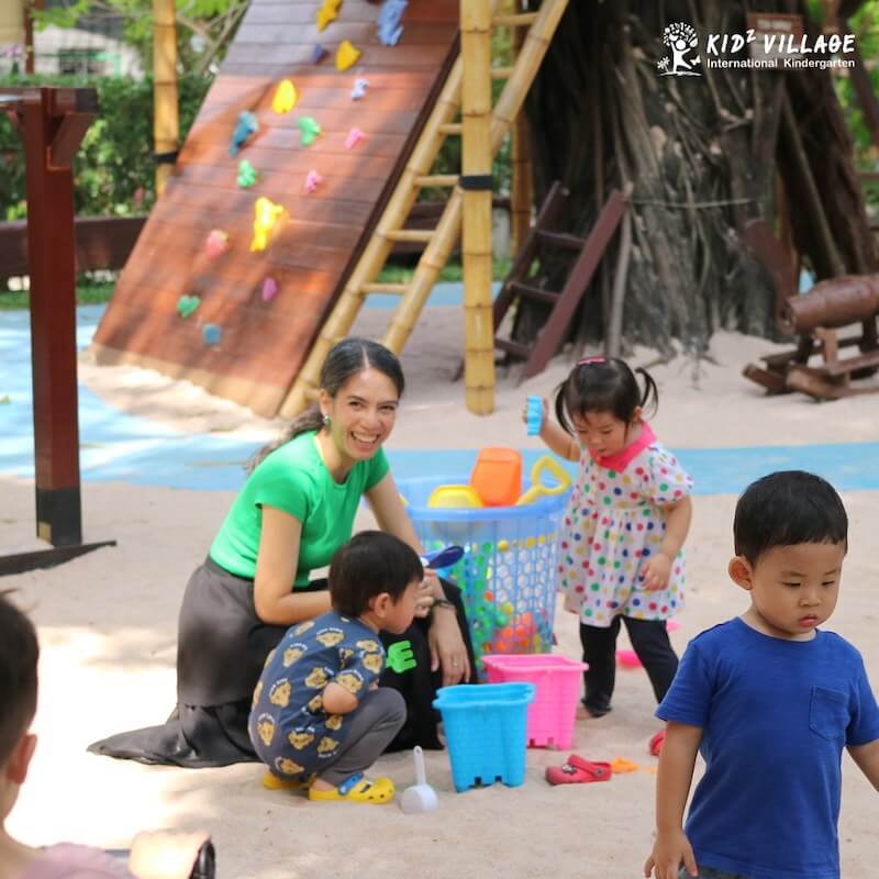 teacher playing with children at the playground
