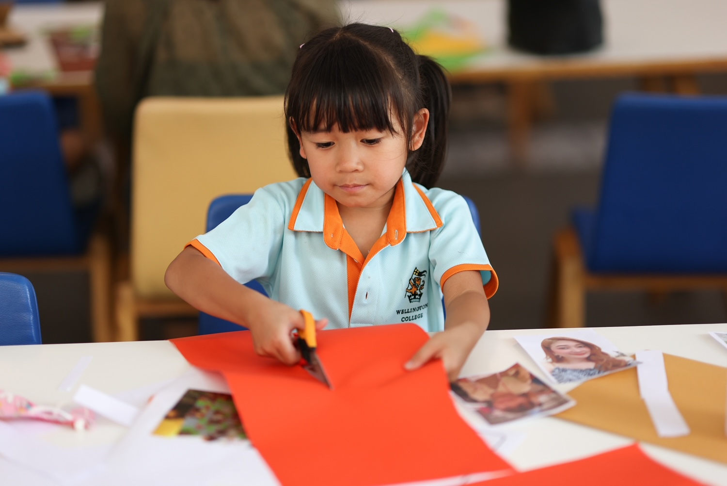 Young girl cutting paper in a school classroom