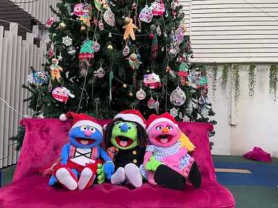 Puppets sitting next to a christmas tree