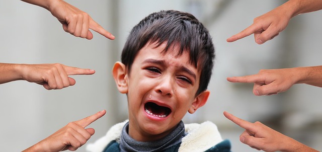 Boy crying with fingers pointed at him being bullied