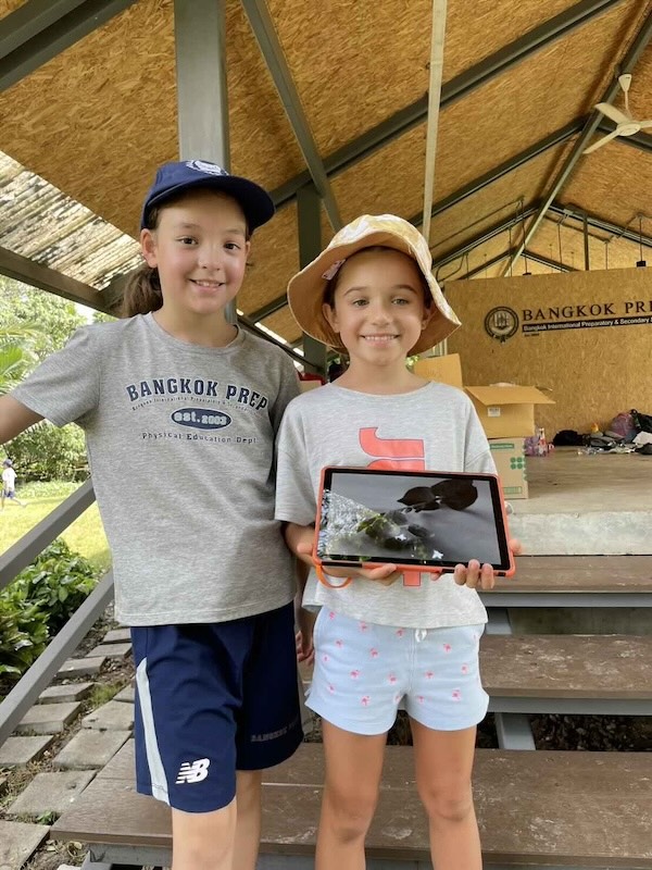 2 kids standing one kids holding ipad