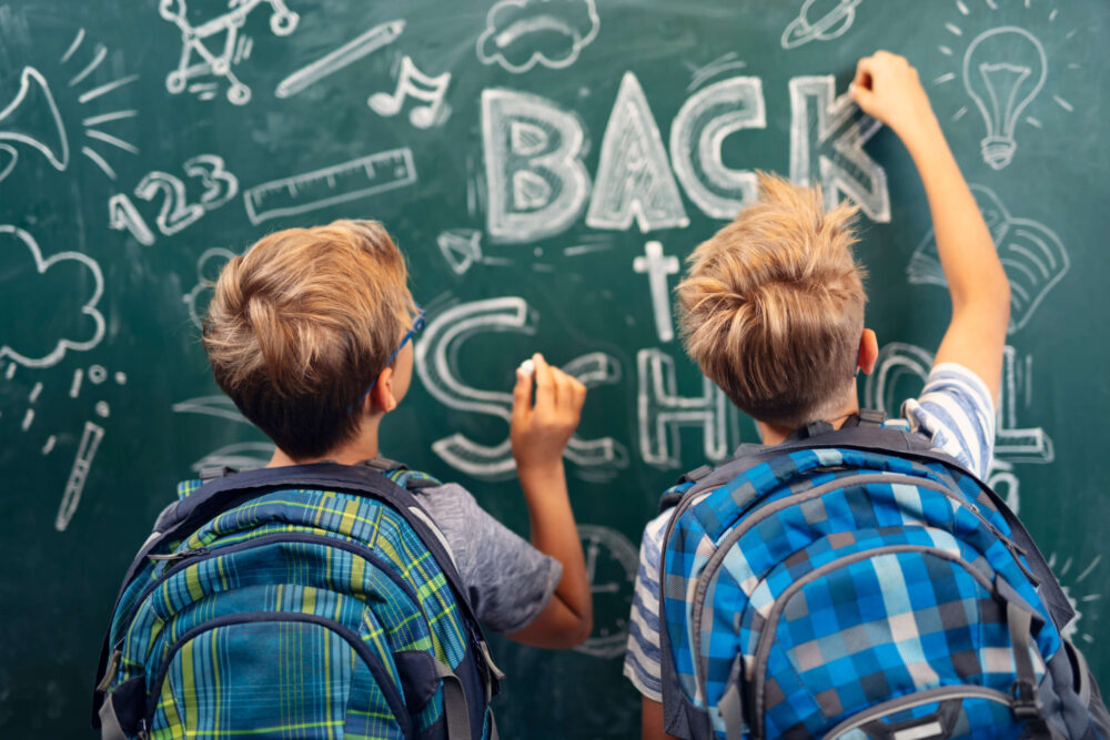 Little boys drawing a back to school painting on the chalkboard